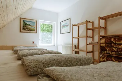 a row of four beds in a room at Dom na Slivnici in Cerknica