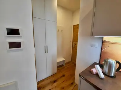 a kitchen with white cabinets and a wooden floor at Apartment Gold in Ljubljana
