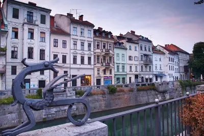 a statue of a boat in a river with buildings at Apartment Gold in Ljubljana
