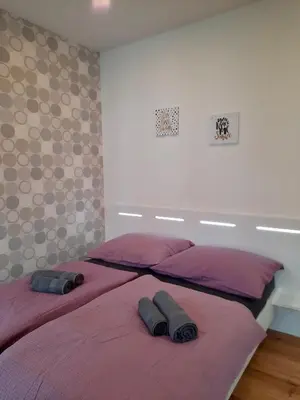 a bedroom with two beds with purple sheets and pillows at Apartment Gold in Ljubljana