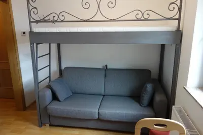 a loft bed with a couch in a room at Apartma Lovor in Bohinj