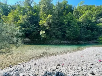 a river with rocks and trees in the background at Hurja Apartments in Kobarid