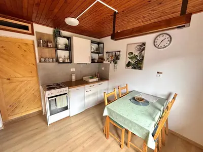 a kitchen and dining room with a table and a clock at Hurja Apartments in Kobarid
