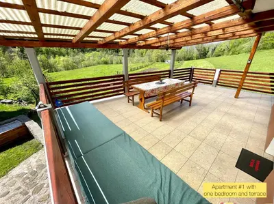 a patio with a table and a wooden roof at Hurja Apartments in Kobarid