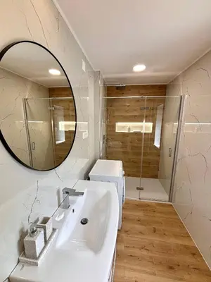 a bathroom with a sink and a mirror and a shower at Hurja Apartments in Kobarid