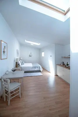 a white bedroom with a bed and a table at Apartment Ana - Karst Cycling Paradise in Dutovlje