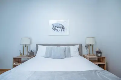 a bedroom with a white bed with two lamps at Apartment Ana - Karst Cycling Paradise in Dutovlje