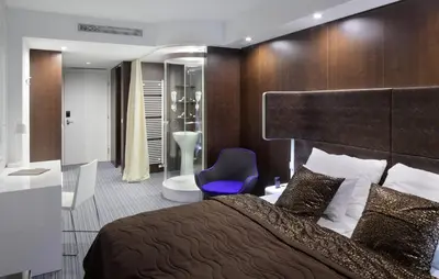 a bedroom with a large bed and a blue chair at Hotel Nox in Ljubljana
