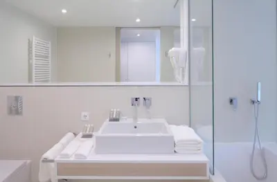 a white bathroom with a sink and a shower at Hotel Nox in Ljubljana