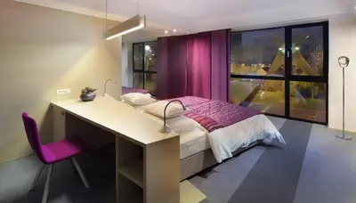 a bedroom with a desk and a bed and a window at Hotel Nox in Ljubljana