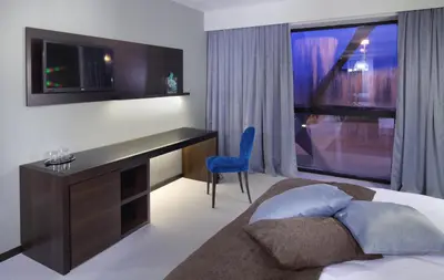 a bedroom with a desk and a bed with a blue chair at Hotel Nox in Ljubljana