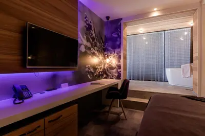 a bedroom with a desk and a bathroom with a tub at Hotel Nox in Ljubljana