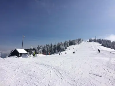 a group of people skiing down a snow covered slope at Apartmaji Snežinka Kope in Slovenj Gradec