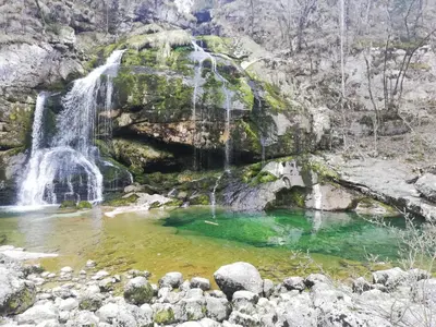 a waterfall on a mountain with a pool of water at Alpine Relax Bovec in Bovec