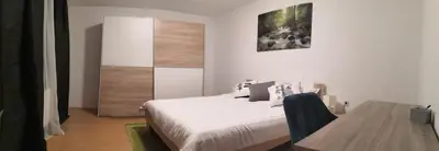 a white bedroom with a bed and a wooden table at Apartmaji Sofia in Maribor