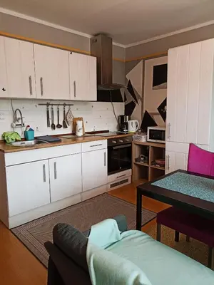 a kitchen with white cabinets and a couch and a table at Apartmaji Sofia in Maribor