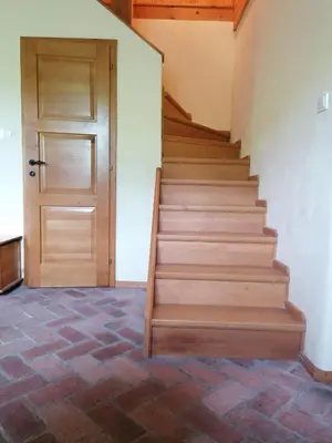 a staircase with a wooden door in a room with a brick floor at Holiday house apartment Voukov mlin in Šmarje pri Jelšah
