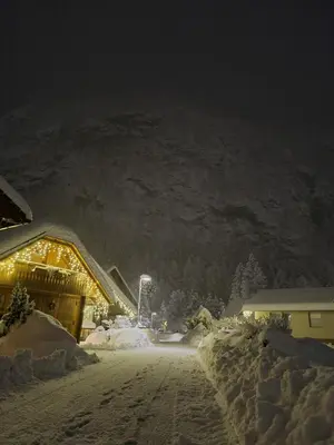 a snow covered village at night with a mountain at Apartma Kreda in Mojstrana