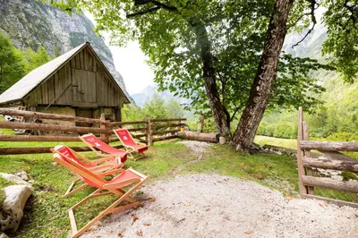two chairs sitting in front of a fence and a barn at Alpine house Antonia in Trenta