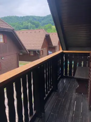 a balcony with a wooden railing with a bench on it at Holiday Cottage Krishtan in Podčetrtek
