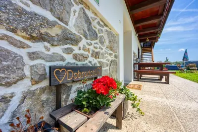 a sign on a stone wall with flowers on a bench at Kolpa reka 