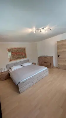 a bedroom with a large bed and a wooden floor at Apartments Ela in Rateče