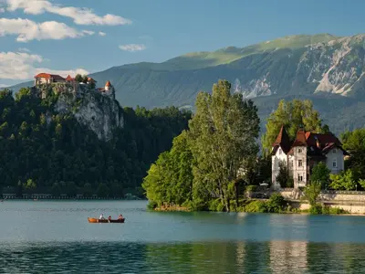 people in a boat on a lake in front of a castle at The Green House in Mojstrana
