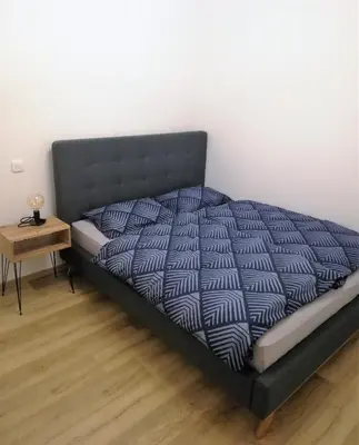a bed in a room with a side table at Apartment Leggero in Moravske Toplice