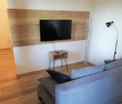 a living room with a blue couch and a flat screen tv at Apartment Leggero in Moravske Toplice