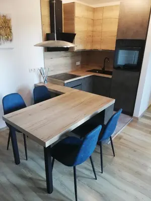 a kitchen with a wooden table and blue chairs at Apartment Leggero in Moravske Toplice