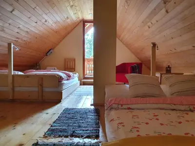 a attic bedroom with two beds and a large window at MOUNTAIN ECO CHALET KONJSKA DOLINA on 1400 m asl -near Pokljuka in Srednja Vas v Bohinju