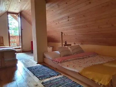 a bed in a room with a wooden wall at MOUNTAIN ECO CHALET KONJSKA DOLINA on 1400 m asl -near Pokljuka in Srednja Vas v Bohinju