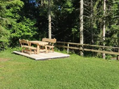 a picnic table and two chairs sitting on a platform in the grass at MOUNTAIN ECO CHALET KONJSKA DOLINA on 1400 m asl -near Pokljuka in Srednja Vas v Bohinju