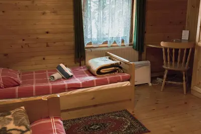 a bedroom with a bed and a chair and a window at PENZIJON URBANC in Lovrenc na Pohorju