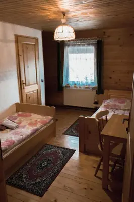 a bedroom with two beds and a table and a window at PENZIJON URBANC in Lovrenc na Pohorju