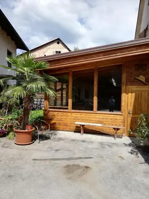 a wooden building with a bench and a palm tree at PENZIJON URBANC in Lovrenc na Pohorju
