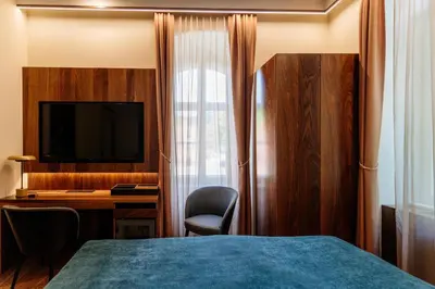 a hotel room with a bed and a desk and a television at Boutique Hotel Dobrna - Terme Dobrna in Dobrna