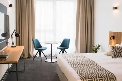 a hotel room with a bed and two chairs and a table at Roko Garni Hotel in Brezovica