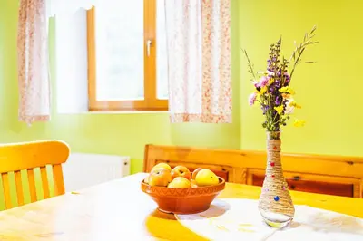 a table with a bowl of fruit and a vase with flowers at Apartment Vrhivšek in Frankolovo