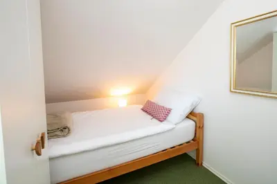 a small bed in a small room with a mirror at Apartmaji Rauter in Bohinj