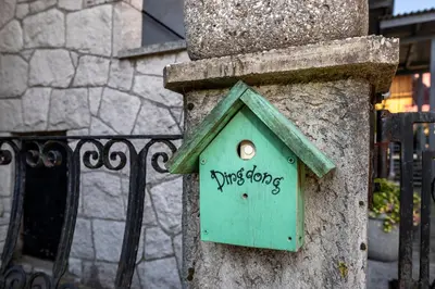 a green bird house on the side of a fence at Apartmaji Rauter in Bohinj