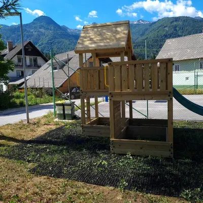 a wooden playground with a slide in a yard at Apartma Nina in Bohinj