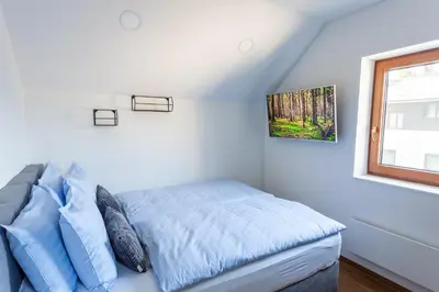 a bedroom with a bed with blue sheets and a window at MY TIME BLED Holiday House with sauna in Zgornje Gorje