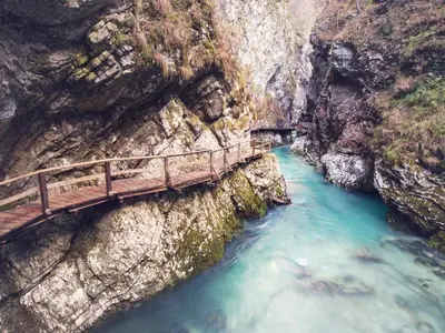 a wooden bridge over a river in a canyon at MY TIME BLED Holiday House with sauna in Zgornje Gorje