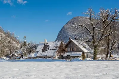 a barn covered in snow in a field at Charming blacksmith`s house @ Lake Bohinj in Bohinj