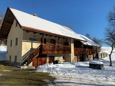 a building with a snow covered roof and a snow covered yard at House Alpine Rose in Mojstrana