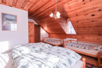 a bedroom with a bed and a wooden ceiling at House Alpine Rose in Mojstrana