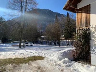 a snow covered yard with a building and a mountain at House Alpine Rose in Mojstrana