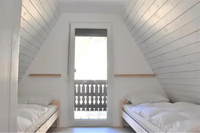 two beds in a attic room with a window at Our Forest House in Tržič