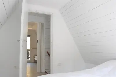 a white room with a bed and a hallway at Our Forest House in Tržič